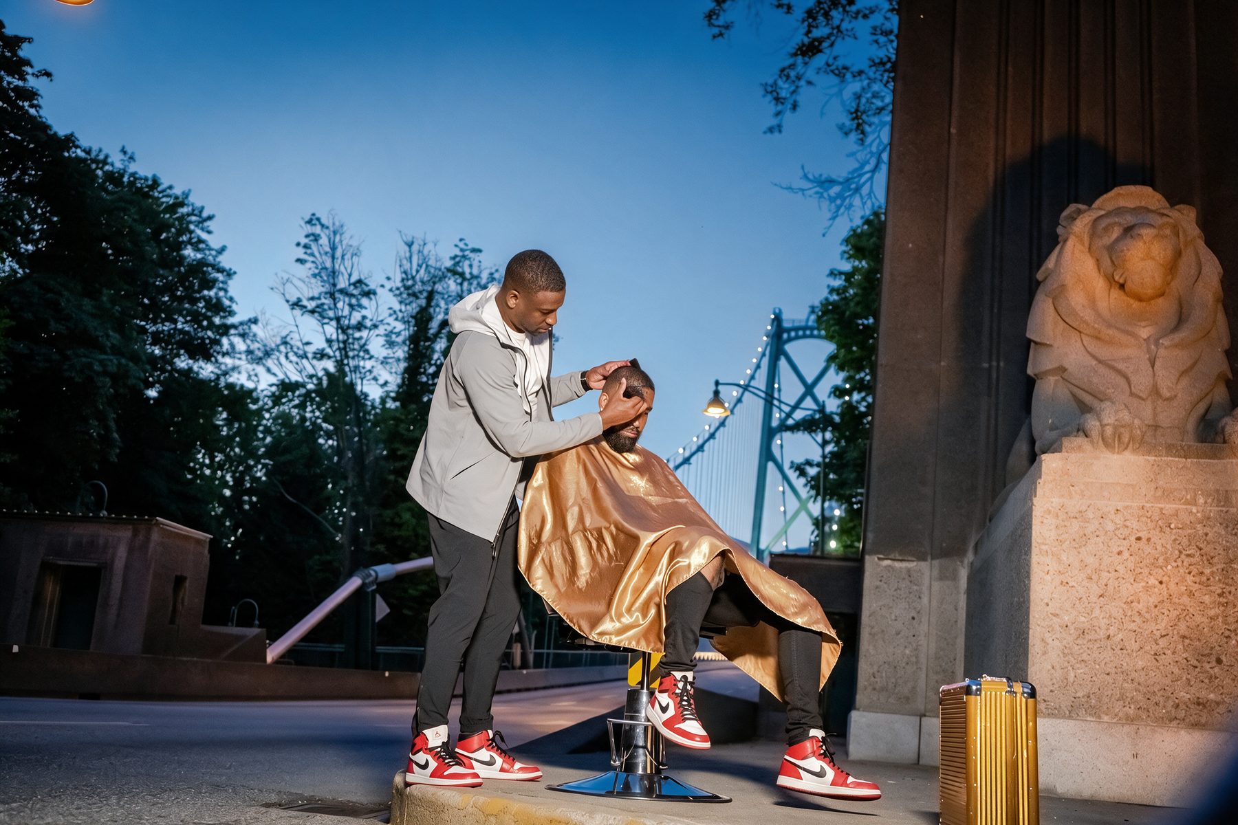 A client in a gold cape in the chair outdoors beside the Lions Gate Bridge