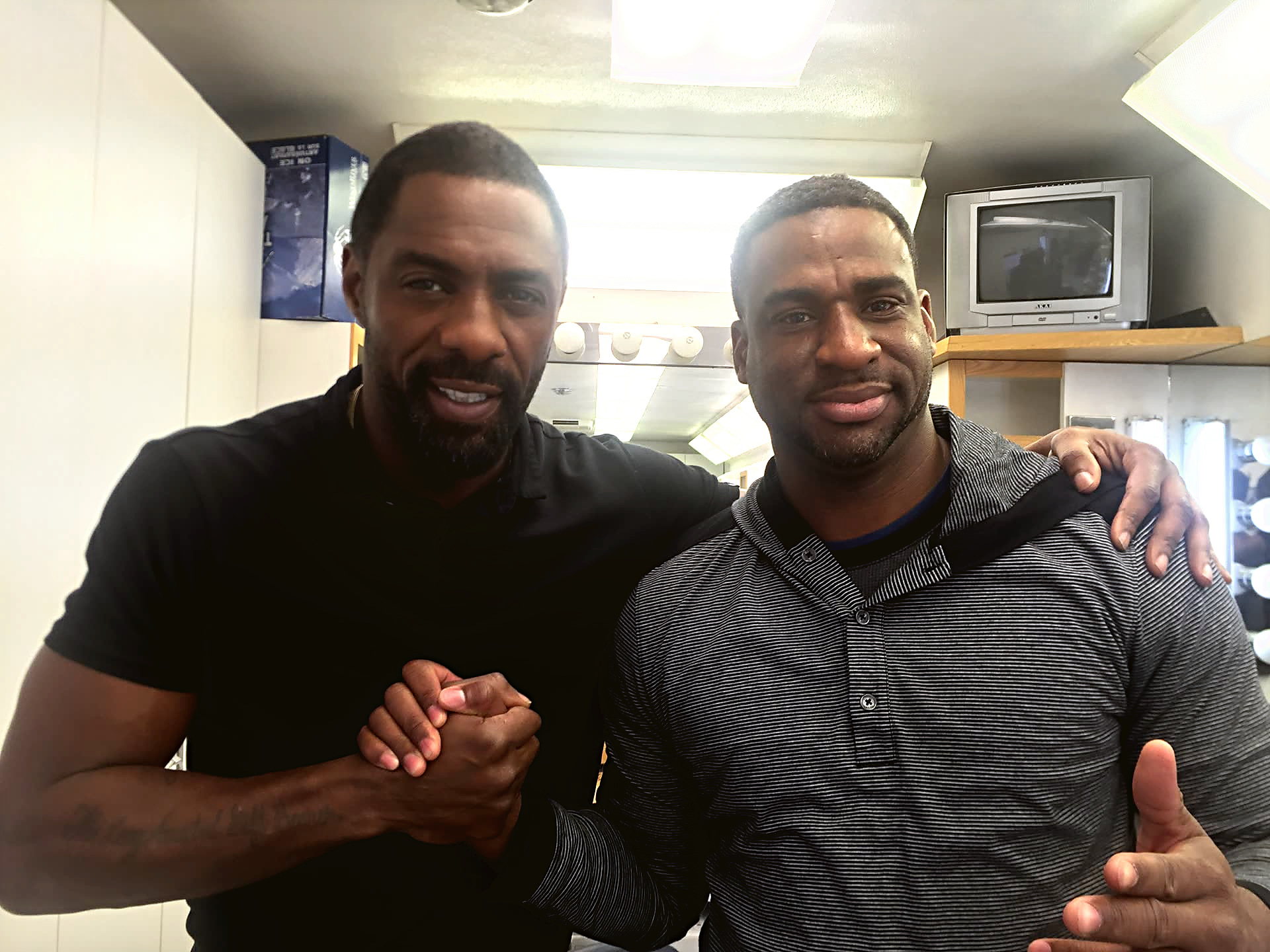 Junior and Idris Elba shake hands under vanity lights