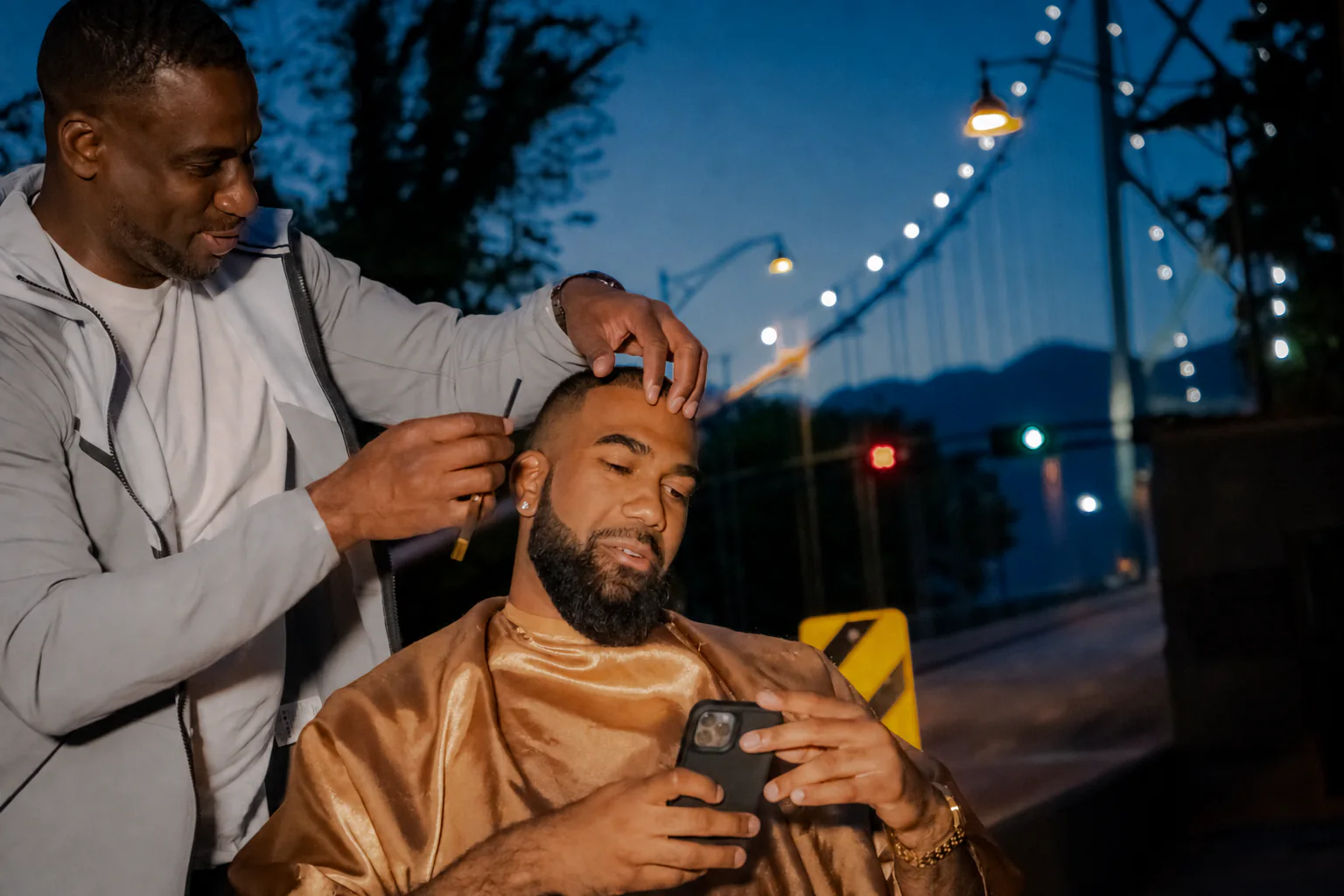 A barber finishing a guest's haircut outside at dusk
